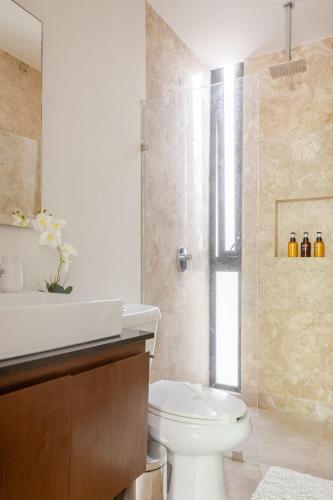 a bathroom with a toilet and a glass shower at Central Playa del Carmen Master Suite with rooftop pool and gym WiFi free parking near beach in Playa del Carmen