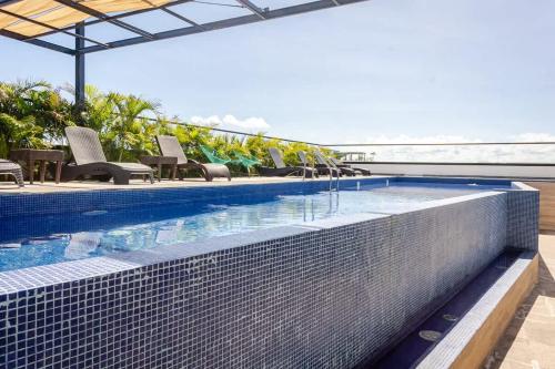 a swimming pool with chairs and the ocean in the background at Central Playa del Carmen Master Suite with rooftop pool and gym WiFi free parking near beach in Playa del Carmen