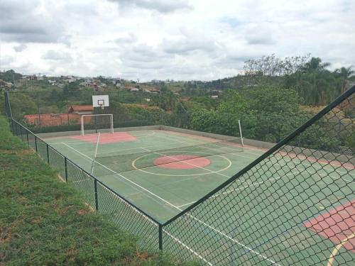 a tennis court with a net and a basketball hoop at Flat encantador com lazer in Serra Negra