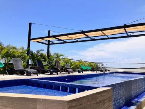 a swimming pool with lounge chairs and a swimming pool at Central Playa del Carmen Master Suite with rooftop pool and gym WiFi free parking near beach in Playa del Carmen