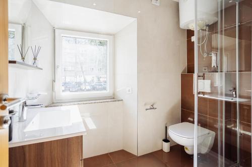 a bathroom with a toilet and a sink and a window at Hotel Šiška in Ljubljana
