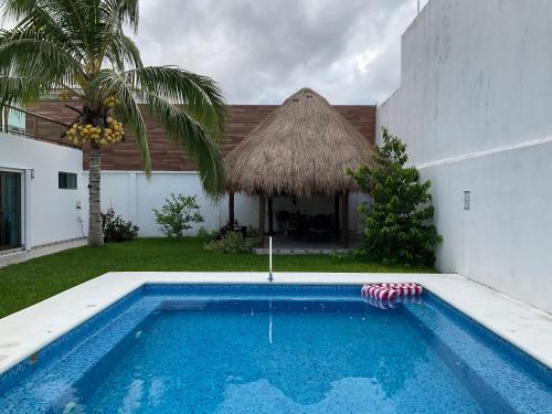 a swimming pool in front of a house with a thatch roof at Casa Palancar with beautiful swimming pool and private palapa in Cozumel