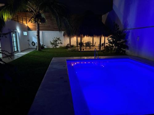 a blue swimming pool in a yard at night at Casa Palancar with beautiful swimming pool and private palapa in Cozumel