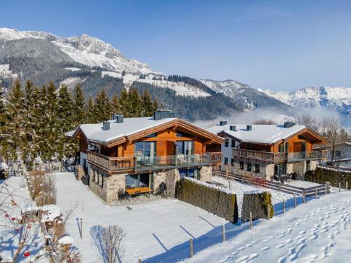 a large wooden house in the snow in the mountains at Chalet Schneelöwe XL in Leogang