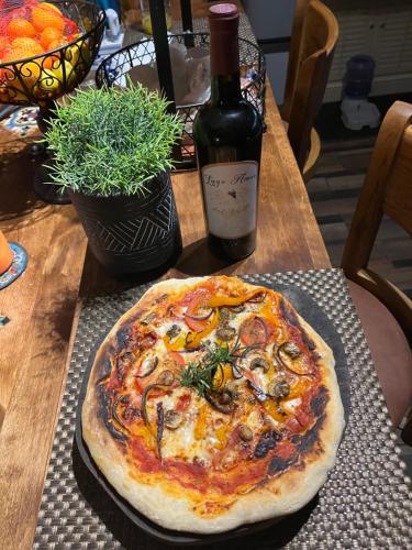 a pizza sitting on a table next to a bottle of wine at Lago Amor del Valle Glamping Grande in San Antonio de las Minas