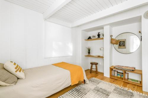 a white bedroom with a bed and a mirror at Luxury A-Frame Retreat in Lake Arrowhead