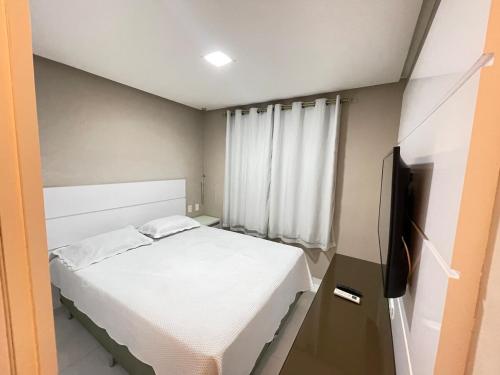 a small bedroom with a bed and a flat screen tv at AP De Alto Padrão - Climatizado, Piscina e Academia No SIM in Feira de Santana