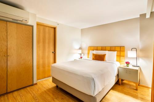 a bedroom with a large white bed and a door at Alteza Polanco in Mexico City