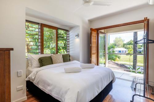 a bedroom with a white bed and a large window at Port Douglas Sea Breeze Villa 2 in Port Douglas