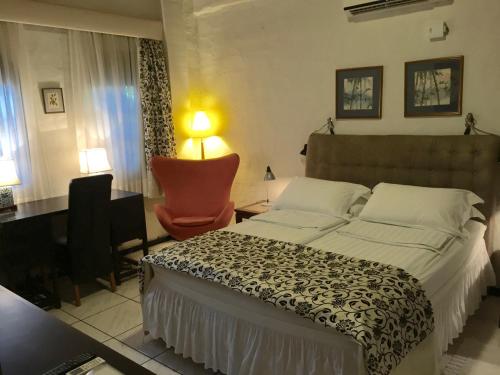 a bedroom with a large bed and a chair at El Refugio in Foz do Iguaçu