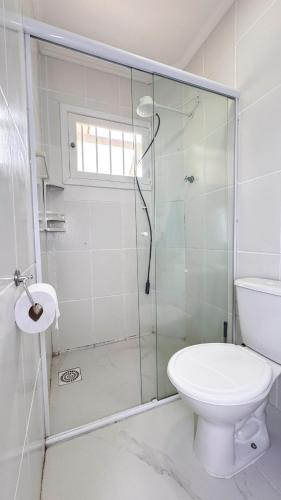a bathroom with a toilet and a glass shower at Casa 3 min da praia 2 suítes churrasqueira garagem in Tramandaí