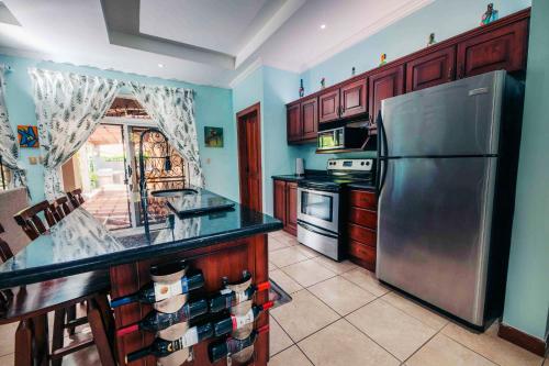 a kitchen with a stainless steel refrigerator and wooden cabinets at Villa Atardecer By Vacation Pura Vida in Bejuco
