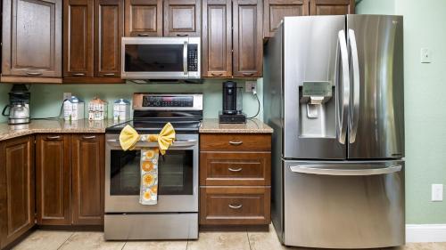 a kitchen with stainless steel appliances and wooden cabinets at Lakefront Retreat - Boat - Fish - Close to all Orlando Parks - Disney - Universal - SeaWorld in Orlando