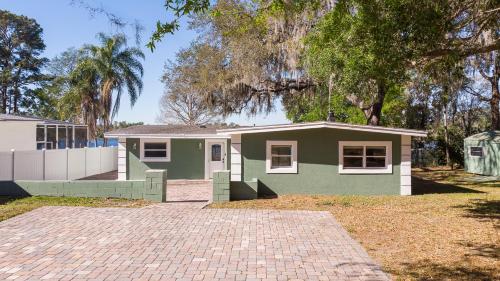 a green house with a brick driveway in front of it at Lakefront Retreat - Boat - Fish - Close to all Orlando Parks - Disney - Universal - SeaWorld in Orlando