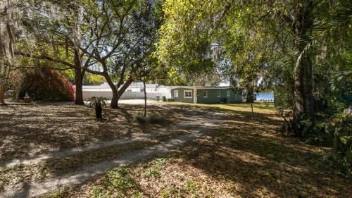 a house in the middle of a park with trees at Lakefront Retreat - Boat - Fish - Close to all Orlando Parks - Disney - Universal - SeaWorld in Orlando