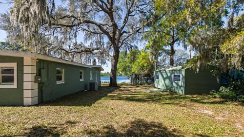 a green building with a tree next to a house at Lakefront Retreat - Boat - Fish - Close to all Orlando Parks - Disney - Universal - SeaWorld in Orlando