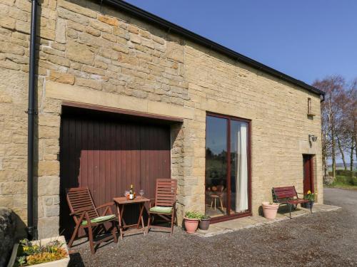 a patio with chairs and a table in front of a building at The Barn at Heath Hall Farm in Sowerby Bridge