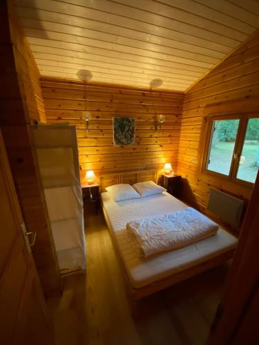 une chambre avec un lit dans une cabane en bois dans l'établissement Chalet en bois sur grand parc arboré tout proche de l océan, à Vendays-Montalivet