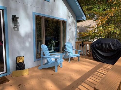two blue chairs sitting on a porch next to a window at Villa MiaNova A Modern Hideout in the Woods in Lake Ariel
