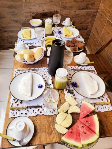 a table with plates of food and fruit on it at Suítes Milagres Bontempo in São Miguel dos Milagres