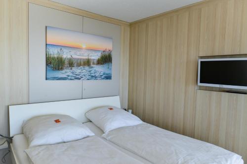a bedroom with a bed and a flat screen tv at Haus Frische Brise 1507 in Cuxhaven