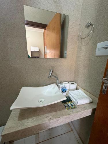 a bathroom with a white sink and a mirror at Pousada Agua Quente in Olímpia