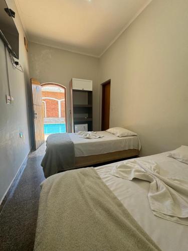two beds in a room with a window at Pousada Agua Quente in Olímpia