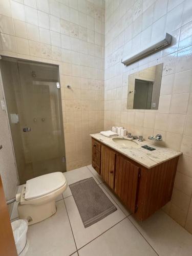 a bathroom with a toilet and a sink and a mirror at Pousada Agua Quente in Olímpia