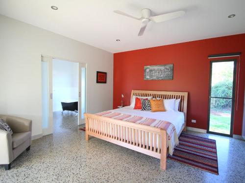 a bedroom with a red wall with a bed and a couch at 3 Bells Alpine Cottage in Bright