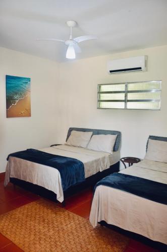 a bedroom with two beds and a ceiling fan at Casa com piscina 500m da praia condomínio Morada da Praia in Bertioga
