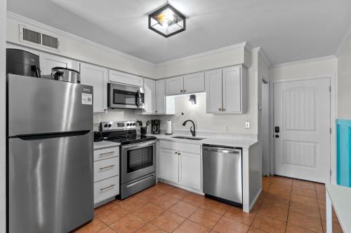 a kitchen with white cabinets and a stainless steel refrigerator at Hang Ten Hideaway, pool, Condo, Parking - 6 person max occupancy in Carolina Beach