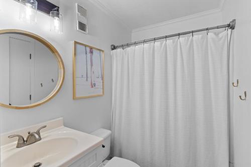 a bathroom with a white shower curtain and a sink at Hang Ten Hideaway, pool, Condo, Parking - 6 person max occupancy in Carolina Beach
