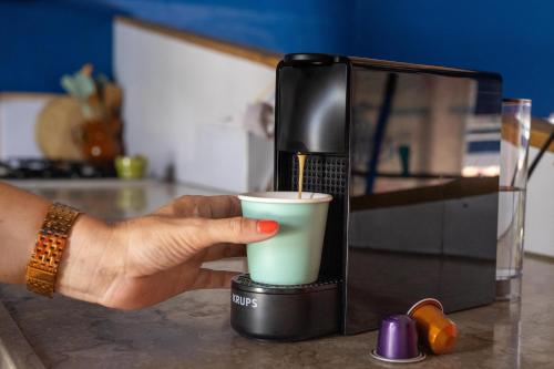 a person is holding a coffee cup in a blender at Luxe centraal gelegen appartment met privé zwembad in Willemstad