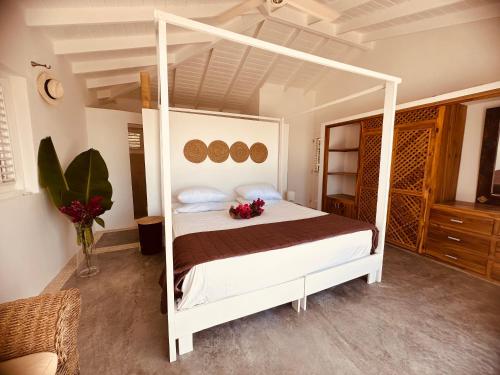 a bedroom with a white canopy bed with flowers on it at Villa blanca chambre d'hôtes vue sur mer in Las Terrenas