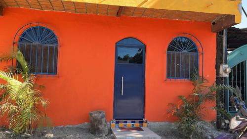 an orange house with a blue door and three windows at Casita Paraiso Escondido in La Peñita de Jaltemba