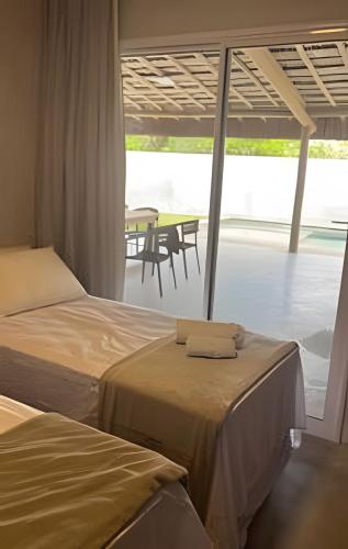 two beds in a room with a view of a table at Mar e descanso - São Miguel in Reduto