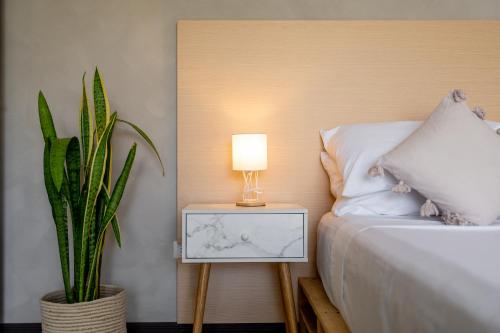 a bed with a lamp on a table next to a plant at House of Turri Suite Views Terrace & Jacuzzi in Verbena Norte