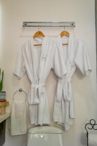 a group of white shirts hanging on a rack above a toilet at House of Turri Suite Views Terrace & Jacuzzi in Verbena Norte