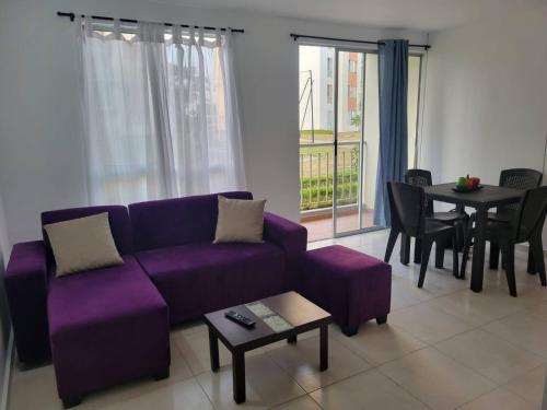 Serenity Inn Jamundi في Jamundí: غرفة معيشة مع أريكة أرجوانية وطاولة