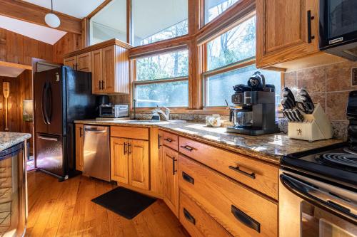 a kitchen with wooden cabinets and a black refrigerator at Whispering Pines Chalet Game Room Fire Pit in Pocono Pines