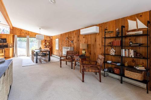 a living room with wooden walls and a table and chairs at Whispering Pines Chalet Game Room Fire Pit in Pocono Pines