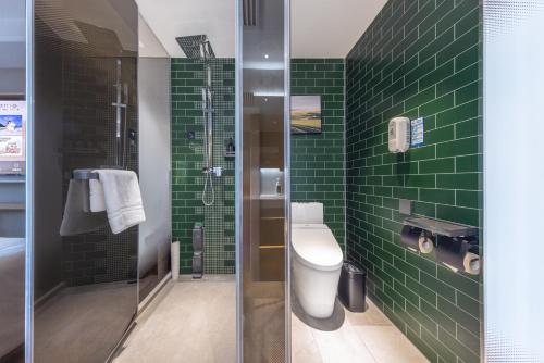 a green tiled bathroom with a toilet and a shower at Atour X Hotel Beijing CBD International Trade Bridge in Beijing