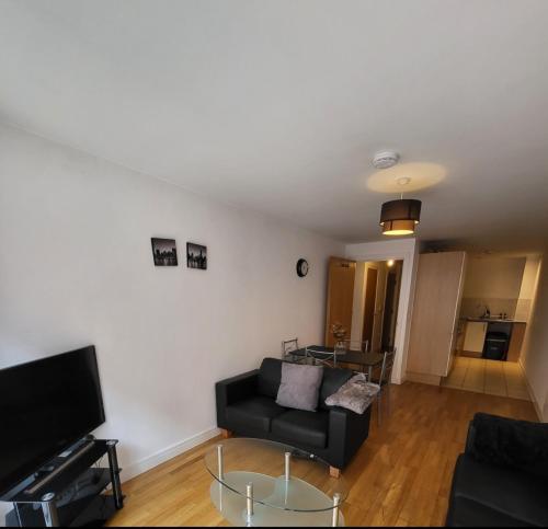a living room with a black couch and a tv at 1 room in shared 2 bedroom apartment R1 in Manchester