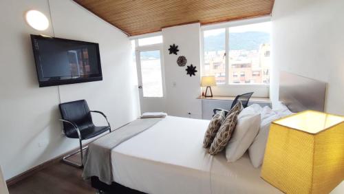 Schlafzimmer mit einem Bett, einem TV und einem Stuhl in der Unterkunft HABITACION 7 Acogedora baño y balcón privado in Bogotá