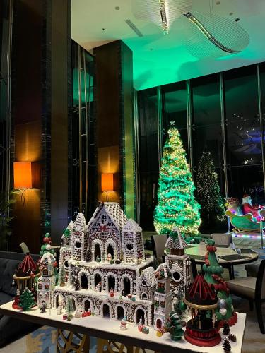 a gingerbread house on a table with a christmas tree at Dannyjuljol homestay in Dompu