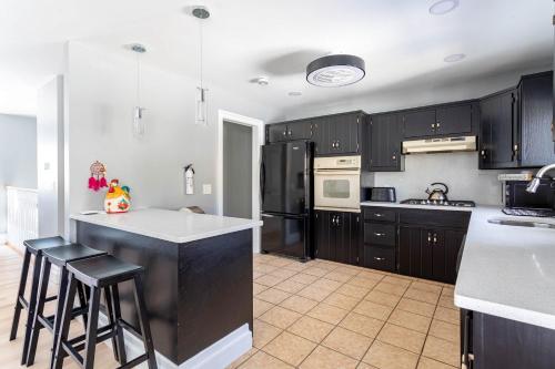 a kitchen with black cabinets and a white counter top at The Woodland Escape Pool Table Fire Pit 4 BD in Tobyhanna