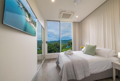 a bedroom with a bed and a large window at 23B Airlie View in Airlie Beach