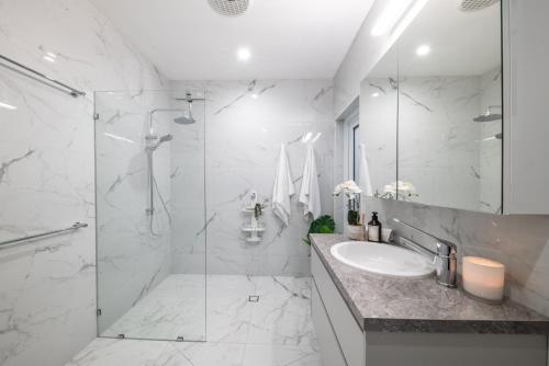 a white bathroom with a shower and a sink at 23B Airlie View in Airlie Beach