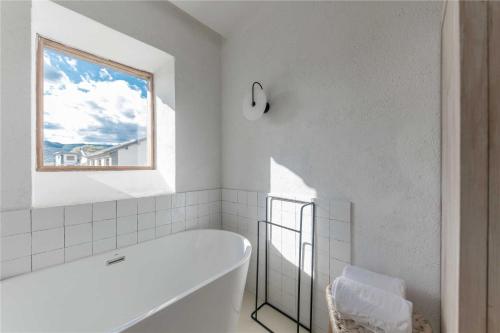 a white bathroom with a tub and a window at Shaxi Ancient Town Shiran Mountain Homestay in Jianchuan