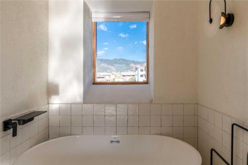 a bath tub in a bathroom with a window at Shaxi Ancient Town Shiran Mountain Homestay in Jianchuan